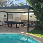 Freestanding bioclimatic pergola beside a swimming pool and garden in Marbella