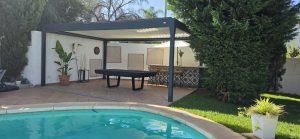 Freestanding bioclimatic pergola beside a swimming pool and garden in Marbella