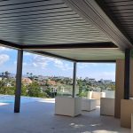 Bioclimatic aluminium pergola covering an outdoor lounge beside a swimming pool in Atalaya, Costa del Sol
