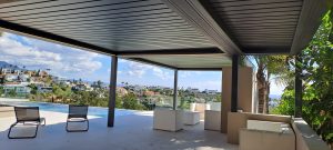 Bioclimatic aluminium pergola covering an outdoor lounge beside a swimming pool in Atalaya, Costa del Sol