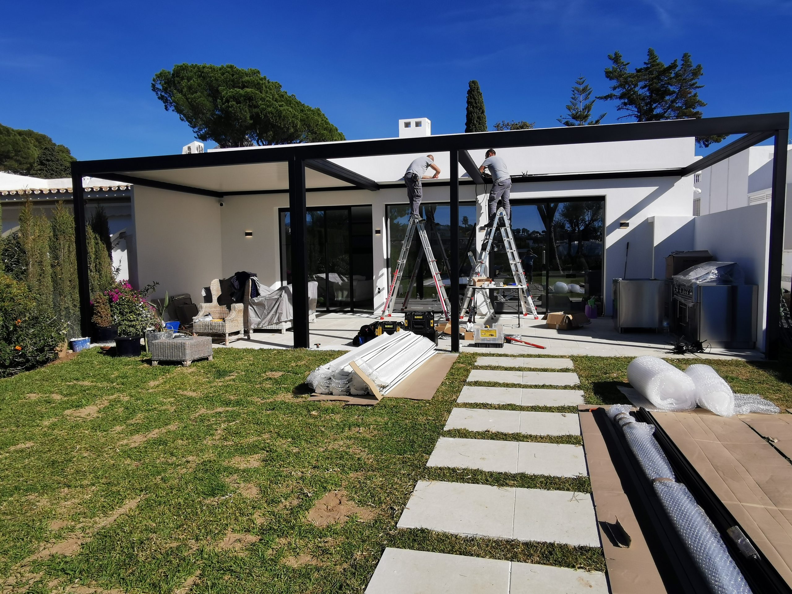 Aluminium pergola being installed beside an existing home, transforming a former lawn area into a covered outdoor space