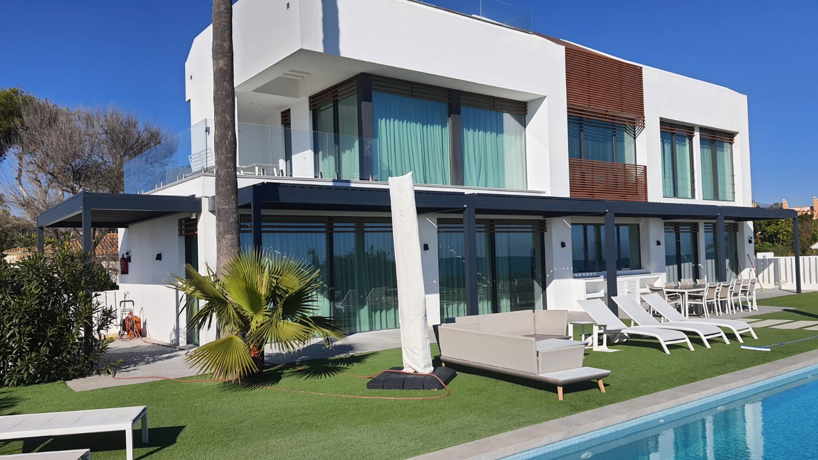 Aluminium bioclimatic pergola integrated into a modern villa terrace beside a swimming pool